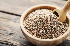 Uncooked quinoa in the wooden bowl, rustic style and selective focus